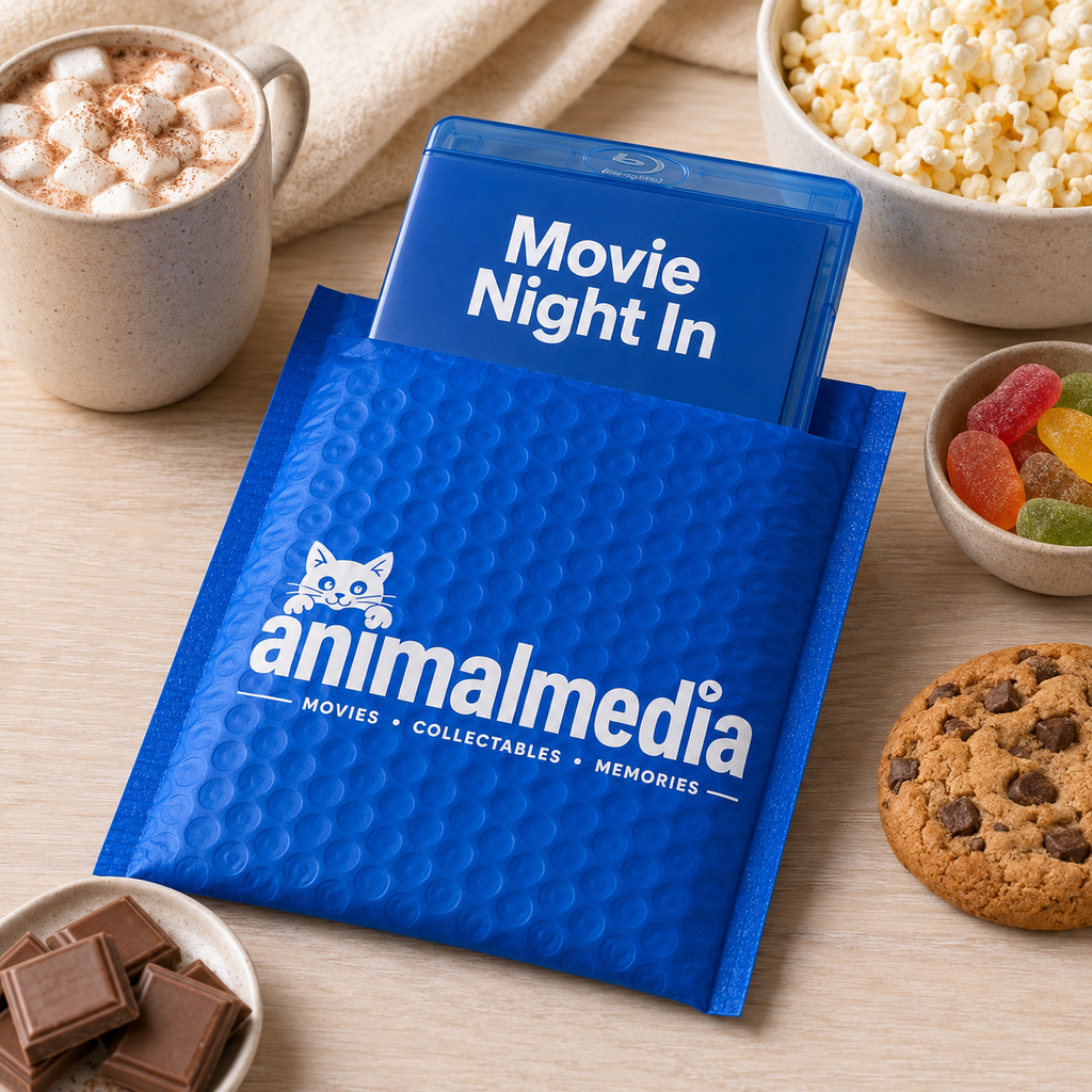 A blue bubble mailer envelope from Animalmedia with a blue insert card reading 'Movie Night In,' styled on a tabletop with popcorn, marshmallows, gummy candies, chocolate bars, and a cookie.