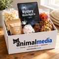 An Animal Media 'Mystery Movie Night In' DVD gift box filled with snacks and treats, set on a wooden table in a cozy indoor setting.